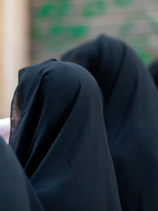 Illustrative: women in full-length black abayas and khimars, seen from behind. Licensed stock photograph, not our own product.