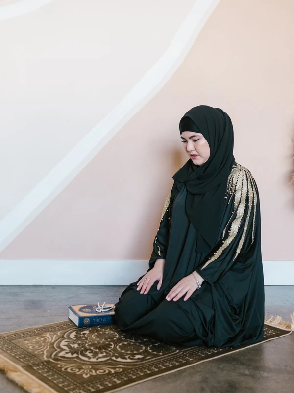 Illustrative: a full-length prayer garment worn kneeling on a prayer rug. Licensed stock photograph, not our own product.