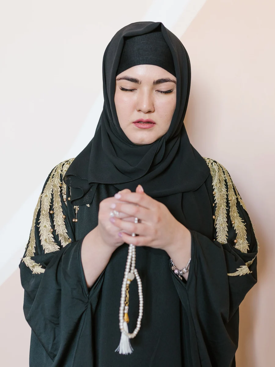 A woman in a black prayer garment holding prayer beads (illustrative stock photo)