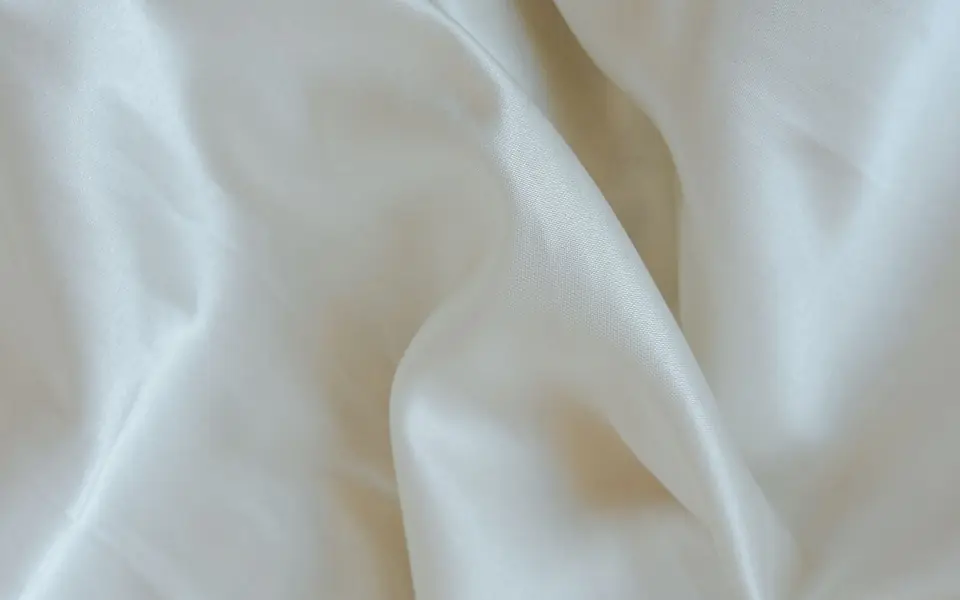Close-up of smooth ivory fabric with a soft sheen