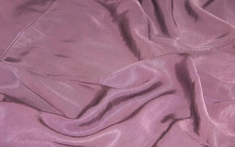 Mauve cupro fabric with a soft sheen in draped folds