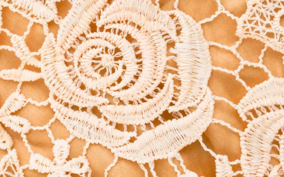 Close-up of cream corded floral lace over a peach cloth