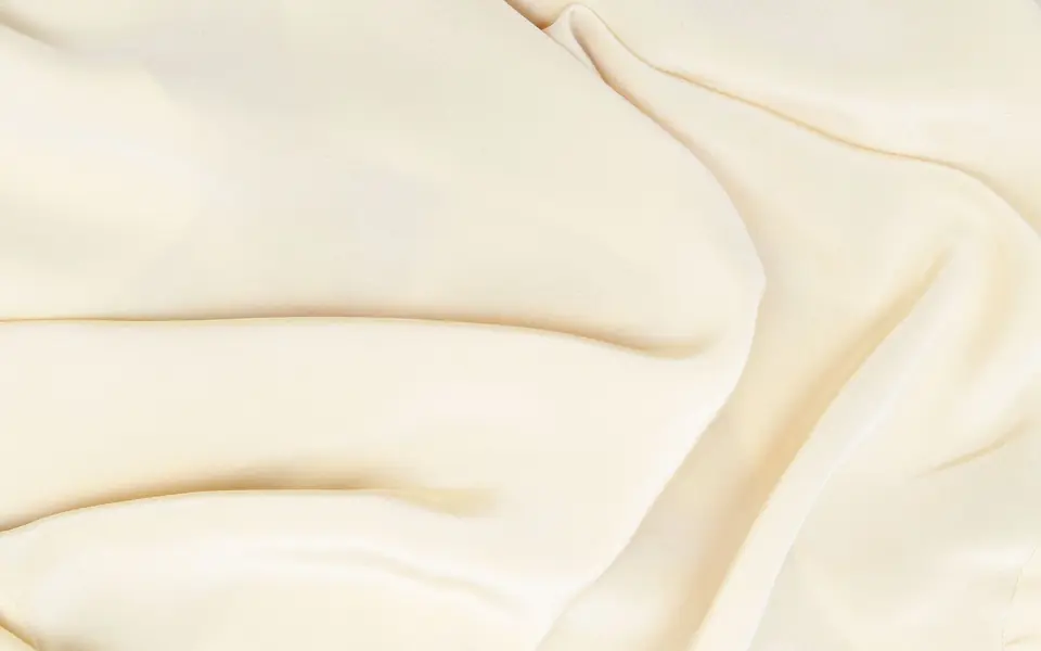 Close-up of cream fabric with a soft sheen in gentle folds