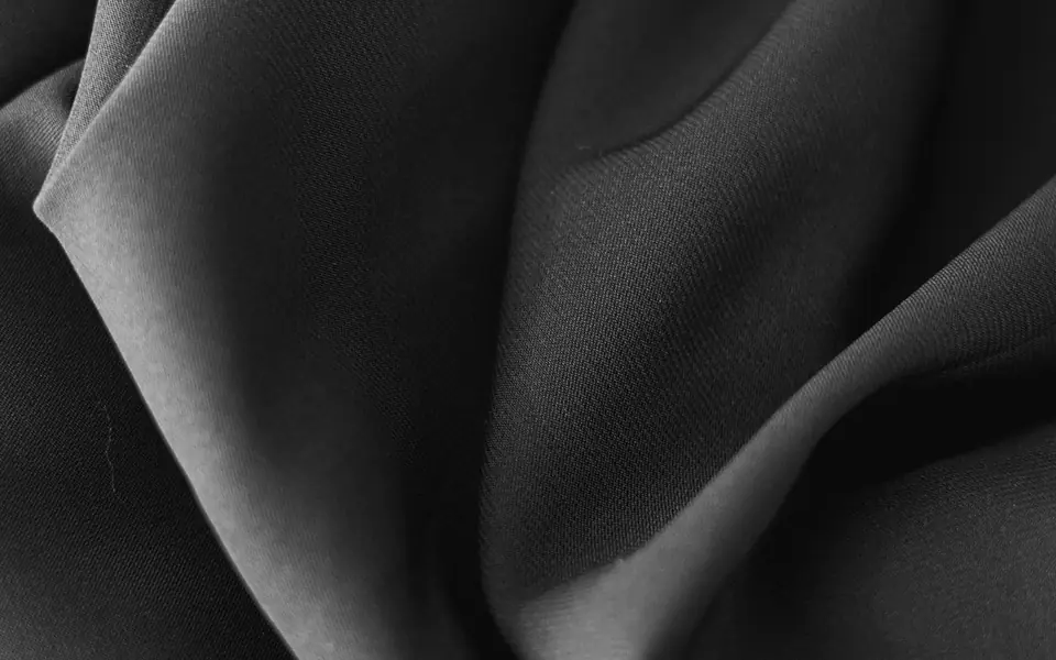Close-up of matte black nida fabric showing its fine weave and soft folds.