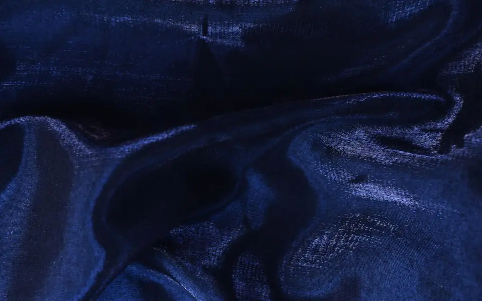 Close-up of crisp midnight blue organza with sharp folds and a sheen