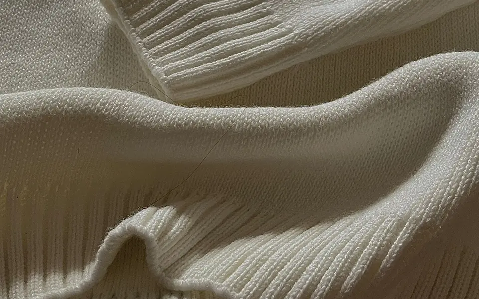 Close-up of a cream ribbed knit with clear vertical ribs