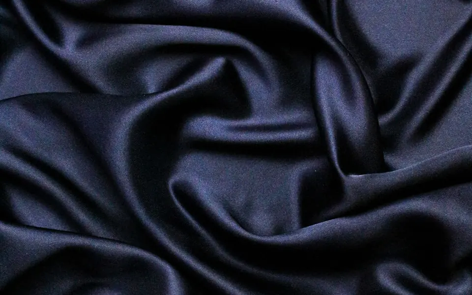 Close-up of dark navy satin with a glossy sheen and deep folds