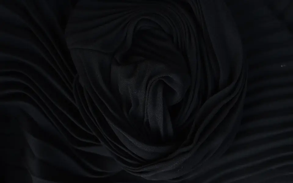 Black fabric gathered into a swirl, with faint texture at the edges