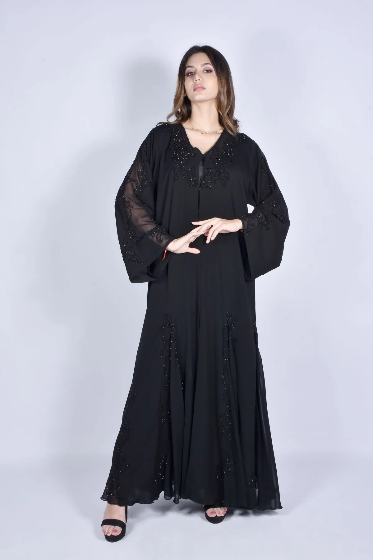 Illustrative: a black abaya with beaded embroidery on the sleeve and front panel. Licensed stock photograph, not our own product.