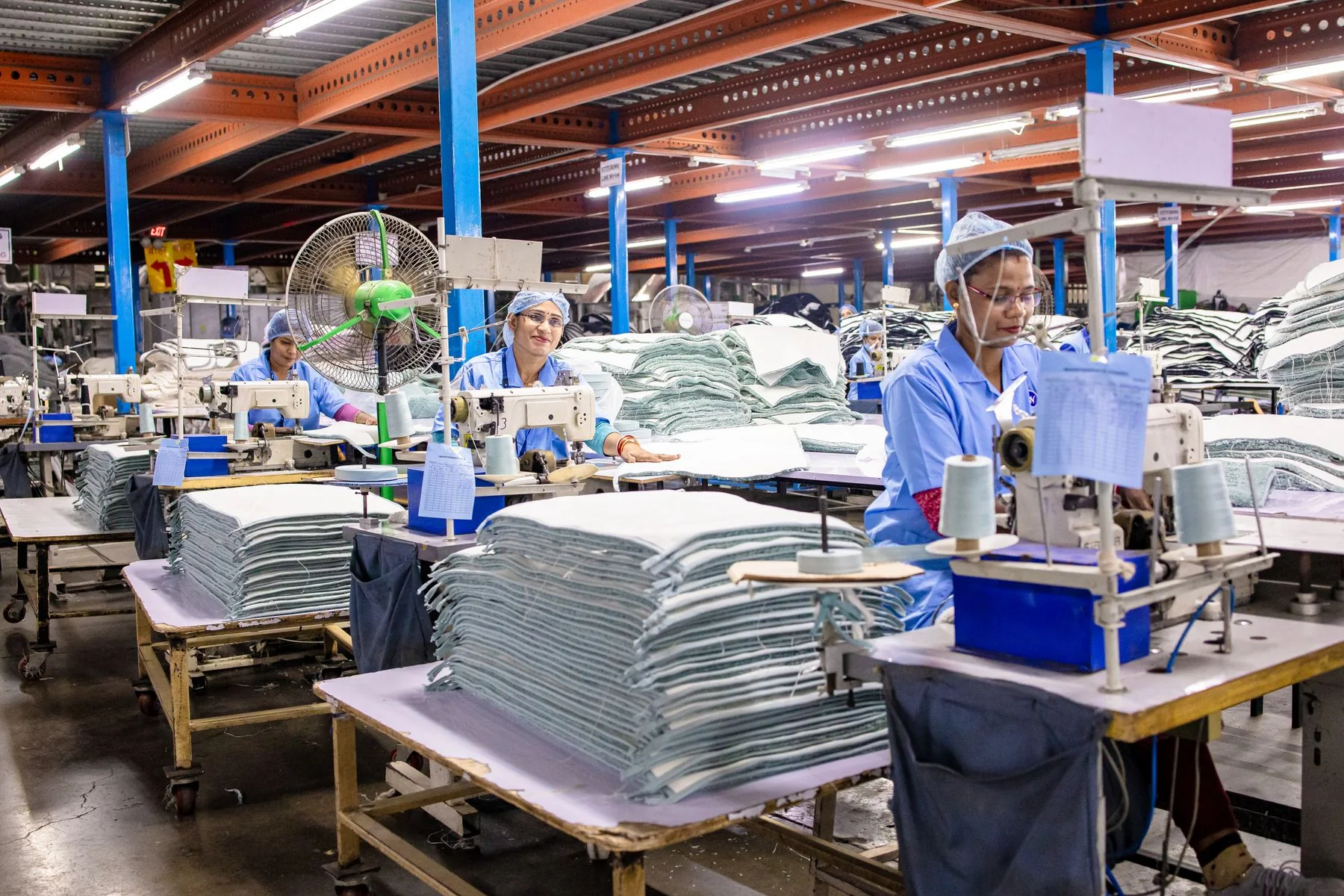 Illustrative: a row of sewing stations on a production floor. Licensed stock photograph, not taken during our production.