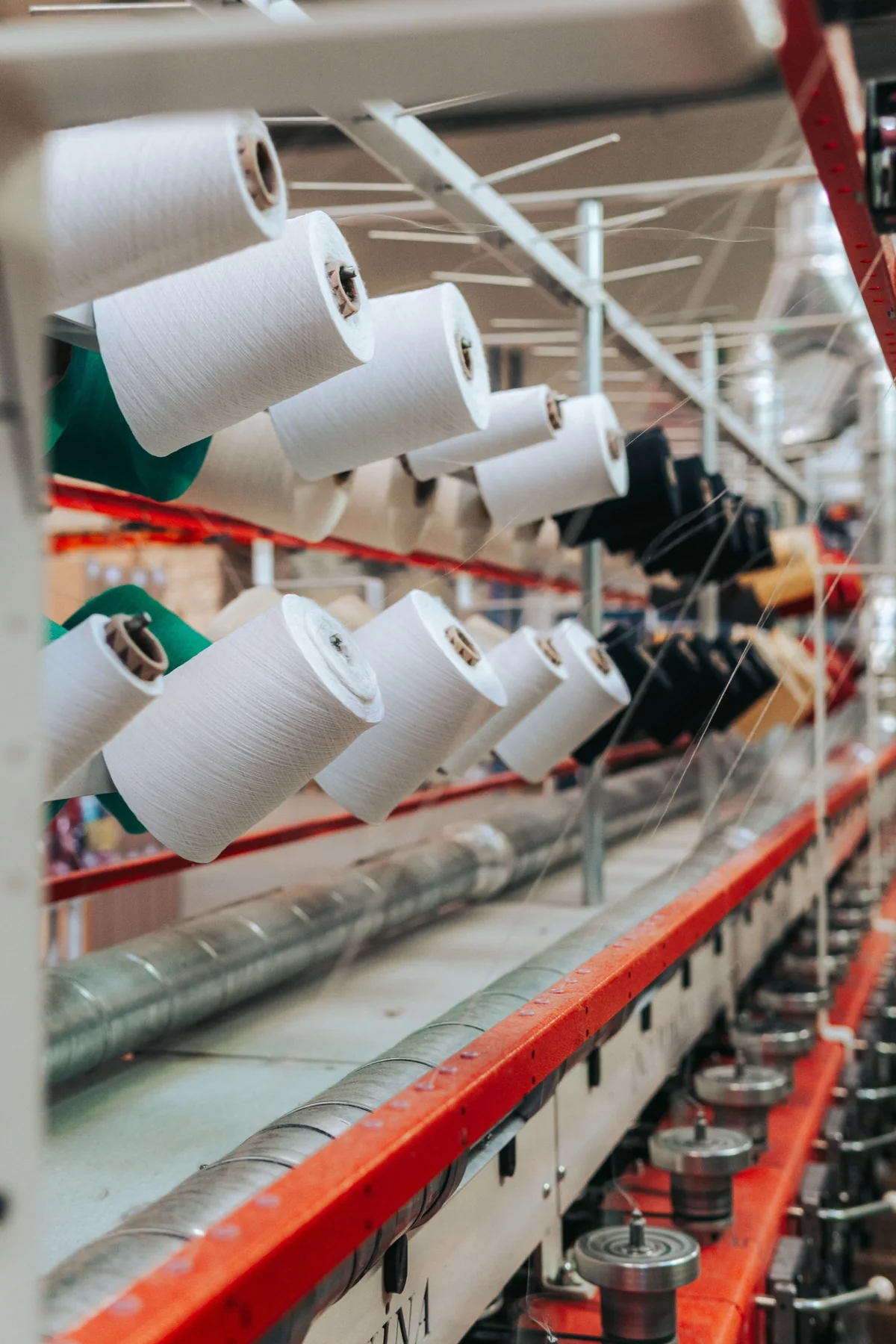 Rows of thread spools in different colours on a factory rack (illustrative stock photo)